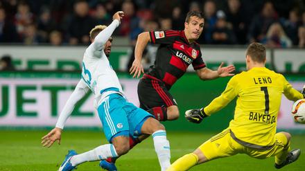 Schalkes Eric Maxim Choupo-Moting (l) erzielt im Zweikampf gegen Leverkusens Giulio Donati (m) und Leverkusens Torwart Bernd Leno (r) das Tor zum 0:1.