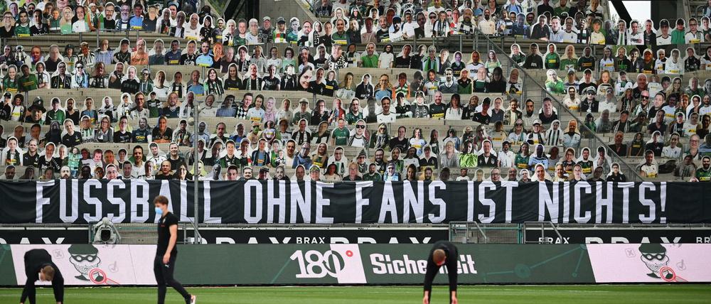 Ein Spruchband im Stadion von Borussia Mönchengladbach, dahinter Pappaufsteller auf der Tribüne. 