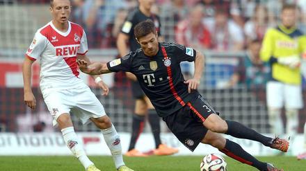 Weltmeisterliche Pose: Bayern-Spieler Xabi Alonso trotzt der Schwerkraft,d er Kölner Adam Matuschyk (l.) staunt.
