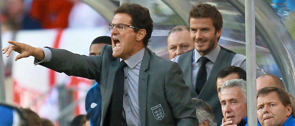Englands Trainer Fabio Capello gibt lautstark Anweisungen, sein Assistent David Beckham im Hintergrund findet's offenbar amüsant.