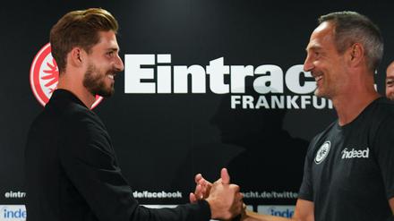 Auf gute Zusammenarbeit: Kevin Trapp (l) und Cheftrainer Adi Hütter begrüßen sich während einer Pressekonferenz von Eintracht Frankfurt. 