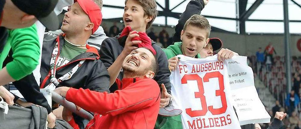 Zaunkönig Sascha Mölders grinst mit den Augsburger Fans um die Wette.