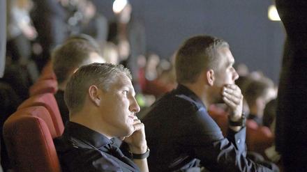 Die Nationalspieler Bastian Schweinsteiger (l.) und Lukas Podolski sitzen bei der Weltpremiere des. Films "Die Mannschaft" im Kino Cinestar im Sony Center am Potsdamer Platz.