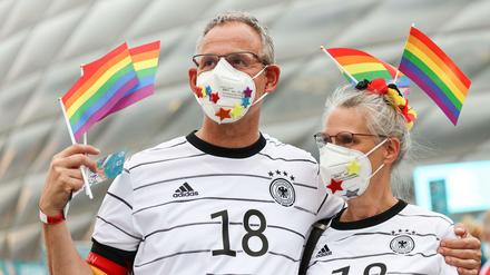 Deutsche Fußballfans schwenken Regenbogenfahnen vor dem Stadion. 
