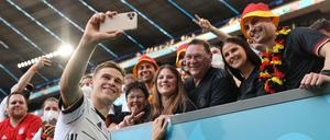 Joshua Kimmich macht ein Selfie mit Fans im Münchner Stadion, die keine Maske tragen.