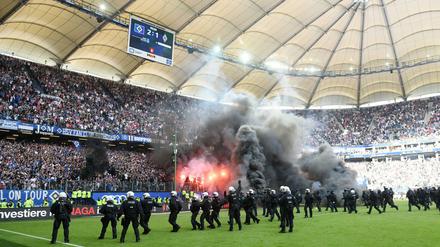 Randalierer zünden kurz vor dem Abpfiff in Hamburg Pyrotechnik, die Polizei sichert das Spielfeld. 