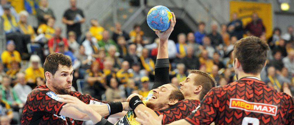 Ringen um den Handball. Jakov Gojun (l) und Bjarki Elisson (2.v.r) von den Füchsen im Kampf um den Ball mit Kim Ekdahl du Rietz von den Löwen. 