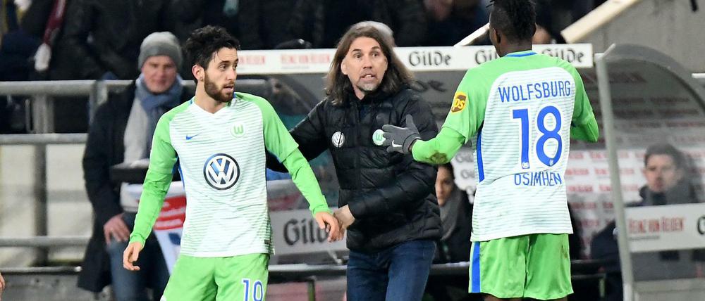 Wolfsburgs Yunus Malli (l) bejubelt sein Tor zum 1:0 gegen Hannover 96 mit Victor Osimhen (r) und Wolfsburgs Trainer Martin Schmidt (M). 