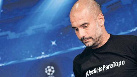 Bayern Münchens Trainer Pep Guardiola weist mit dem T-Shirt-Aufdruck #JusticiaParaTopo auf den Unfalltod eines argentinischen Journalisten bei der WM hin.