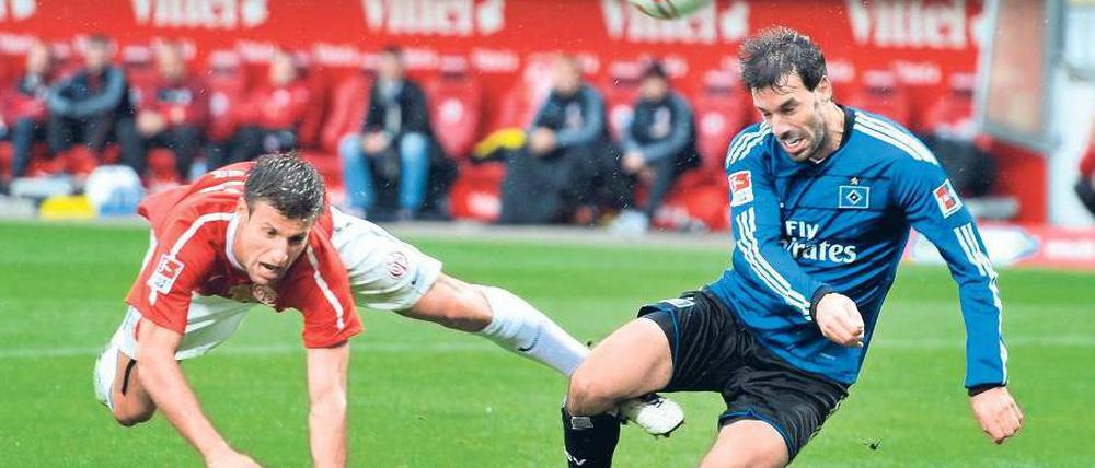 Zweiter Sieger. Marco Caligiuri (l.) kommt gegen HSV-Stürmer Ruud van Nistelrooy zu spät, Mainz fiel auf Rang zwei zurück. Foto: dapd