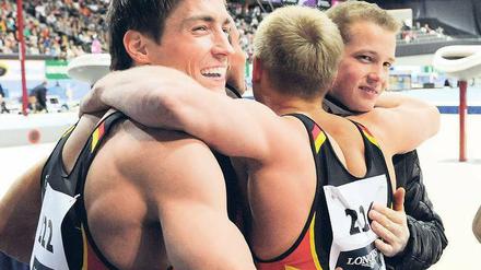 Zusammen ist man weniger allein. Philipp Boy, Eugen Spiridonov und Fabian Hambüchen (von links) freuen sich über ihre WM–Bronzemedaille im Mannschaftswettbewerb. Foto: dpa