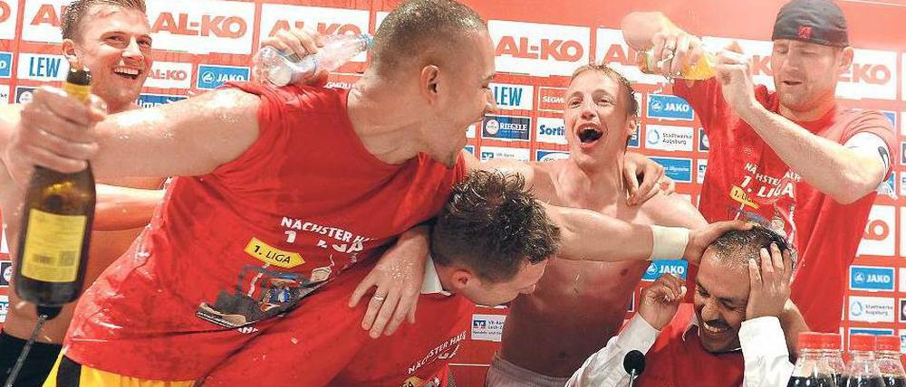 Ihr Kommentar zum Spiel, bitte. Augsburgs Trainer Jos Luhukay (rechts unten) und seine Spieler geben nach dem Aufstieg eine ziemlich feuchte Pressekonferenz. Foto: AFP