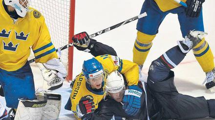 Eiskalter Schwitzkasten. Schweden spielt eine starke WM, hier ringt Carl Gunnarsson den Amerikaner Yan Stastny nieder. Foto: AFP