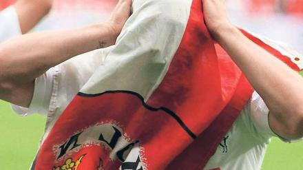 Das Gesicht des Vereins. Lukas Podolski jubelte nach dem Sieg in Leverkusen hinter einer Vereinsfahne – als wolle er allen klar machen, dass der 1. FC Köln nicht nur aus ihm selbst besteht. Zuvor hatte der Nationalspieler zwei Tore erzielt. Foto: dapd
