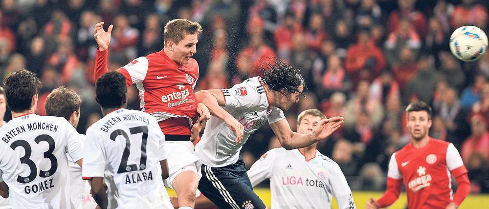Ganz Bayern schaut zu. Mehrere Münchner betrachten interessiert und mehr oder weniger tatenlos, wie der Mainzer Niko Bungert das 3:1 erzielt. Foto: dapd