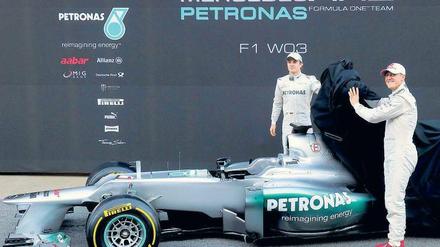 Schaut her, da ist es. Michael Schumacher und Nico Rosberg lüften das Geheimnis von Mercedes und haben offensichtlich viel Freude daran. Das neue Auto fahre sich auf jeden Fall zuverlässiger als das alte, sagen die beiden Formel-1-Piloten. Foto: AFP
