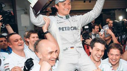 Pose mit Pott. Für seinen ersten Sieg wird Nico Rosberg auf Händen getragen. Foto: dapd
