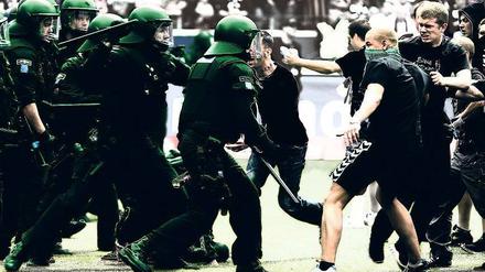 Die Ausrüstung macht den Unterschied. Im Gruppenverhalten sind sich Ultras und Polizisten ähnlich. Die Szene zeigt eine Ausschreitung beim Spiel Eintracht Frankfurt gegen 1860 München im April 2012. Foto: dpa
