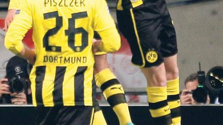 Und sie fliegen weiter. Dortmunds überragender Spieler Mario Götze feiert Marco Reus und dessen Tor zum 1:0, das der Partie schon früh die entscheidende Richtung gab. Foto: dapd