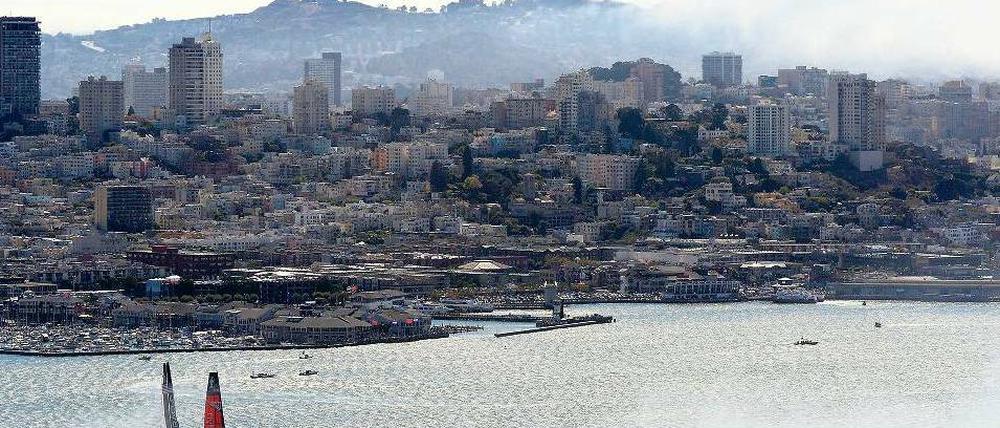 Stadtarena. Vor der Kulisse von San Francisco und 80 000 Zuschauern am Hafen sind die Teams aus Neuseeland (rotes Boot) und den USA (schwarzes Boot) meist gleichauf. Foto: dpa