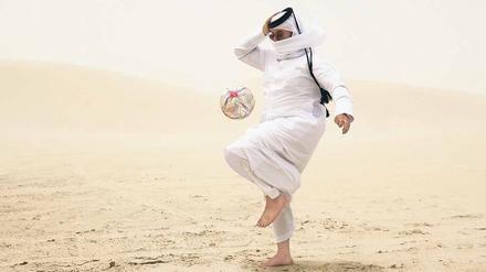 Ein Einwohner von Katar spielt mit einem Fußball.