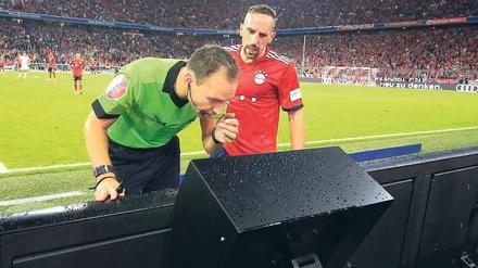 Ich habe dich auf dem Schirm. Schiedsrichter Bastian Dankert (links) beim Videostudium in der Arena von München, Franck Ribéry vom FC Bayern guckt mit.