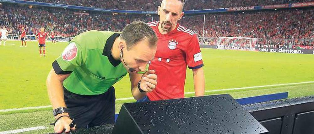 Ich habe dich auf dem Schirm. Schiedsrichter Bastian Dankert (links) beim Videostudium in der Arena von München, Franck Ribéry vom FC Bayern guckt mit.