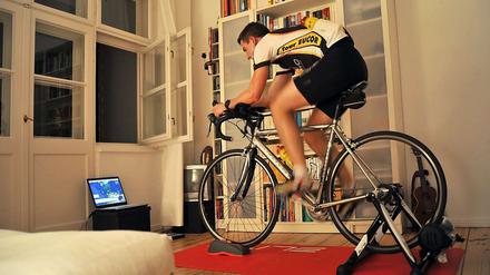 Auf der Stelle. Arne Bensiek fährt in seinem Wohnzimmer Fahrrad.