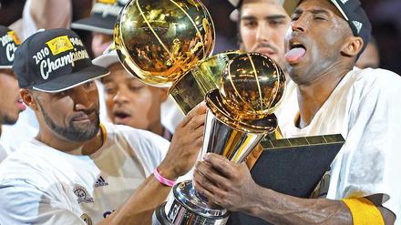  Pokalrunde: Lakers-Spieler Kobe Bryant (rechts) hält die Trophäe für den "Most Valuable Player", sein Teamkollege Derek Fisher reicht ihm den Teampokal dazu.