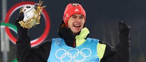 Der nordische Kombinierer Vinzenz Geiger ist neuer Olympiasieger und jubelt bei der Siegerehrung.