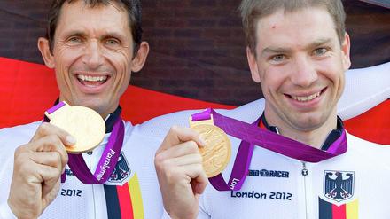 Die Olymiasieger Michael Teuber (l.) und Tobias Graf posieren mit ihren Gold-Medaillen nach ihrem Erfolg im Zeitfahren.