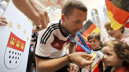 Schau mal her, so sieht ein Weltmeister aus. Lukas Podolski lässt sich nach dem WM-Titel in seiner Heimat Köln feiern.