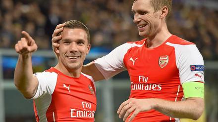 Lukas Podolski (links) trifft, Per Mertesacker freuts.
