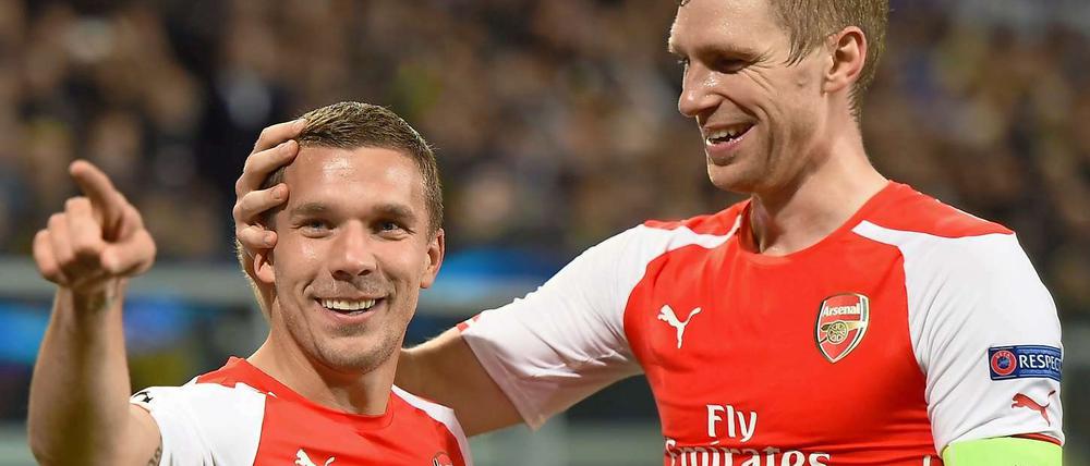 Lukas Podolski (links) trifft, Per Mertesacker freuts.