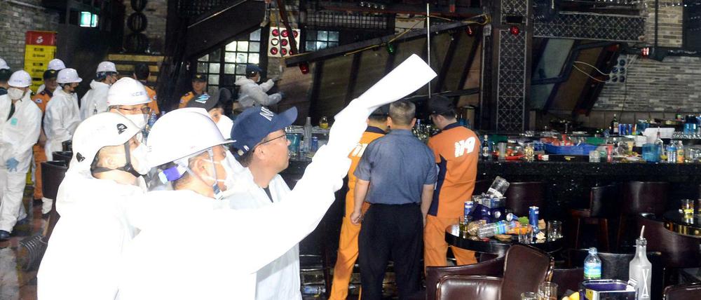Feuerwehrmänner und Sicherheitskräfte untersuchen den Nachtclub in Gwangju nach dem Unglück.