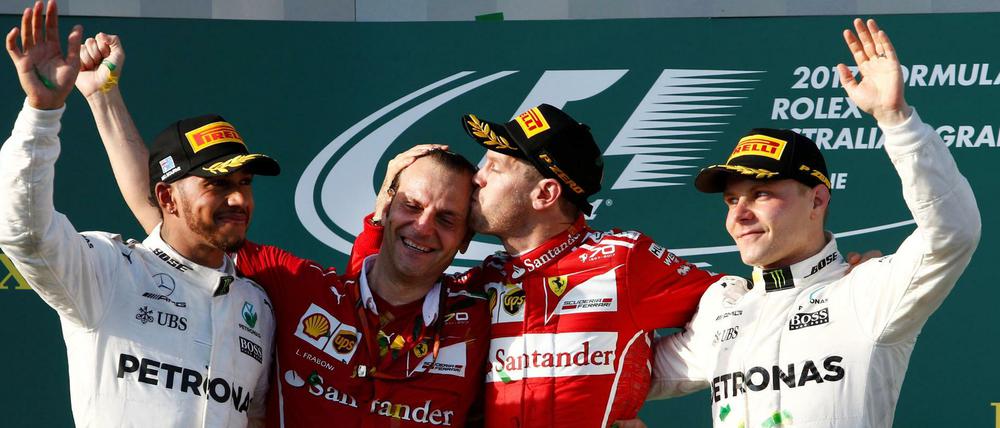 Sebastian Vettel knutscht Ferrari-Vertreter Luigi Fraboni, Mercedes-Piloten Lewis Hamilton und Valtteri Bottas schauen zu.