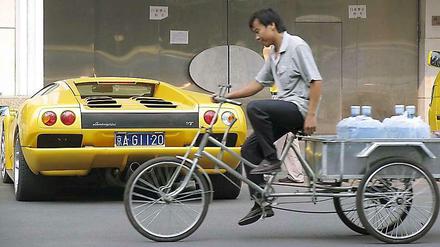 Fahrrad und Luxuskarosse - in China sind die sozialen Unterschiede groß. 
