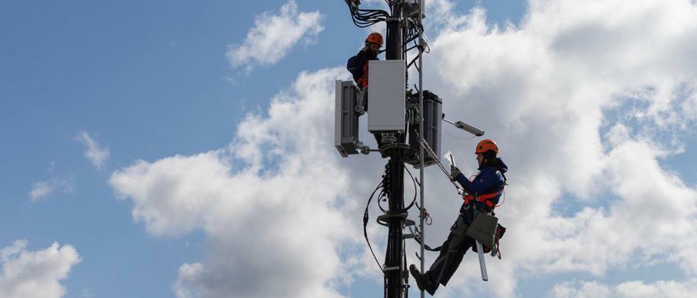 Techniker instalieren eine Antenne für das 5G Funknetz auf einem Hausdach in der schweizer Hauptstadt Bern. 