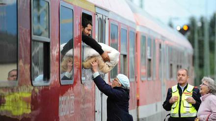 Eine ältere Frau reicht am Bahnhof in Freilassing (Bayern) einem mit einem Sonderzug aus Wien angekommenen Flüchtling eine von ihr gespendete Decke durch das Fenster des Waggons, bevor er nach einer kurzen Registrierung weiter nach Hanau fährt.
