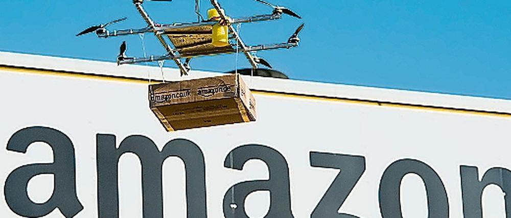 Eine Drohne mit einem Amazon-Paket schwebt vor dem Amazon Logistikzentrum Leipzig.