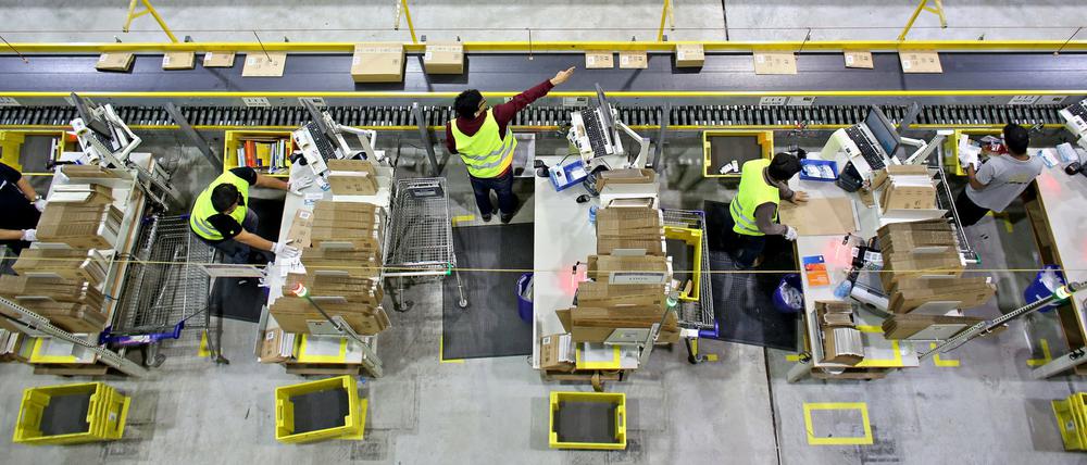 Mitarbeiter des Amazon-Logistikzentrums in Leipzig (Sachsen) verpacken Waren für den Paketversand.