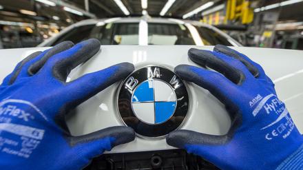 Ein Mitarbeiter montiert im BMW-Werk in Dingolfing (Bayern) ein BMW-Emblem auf den Kofferraumdeckel eines Fahrzeugs der 7er Reihe.