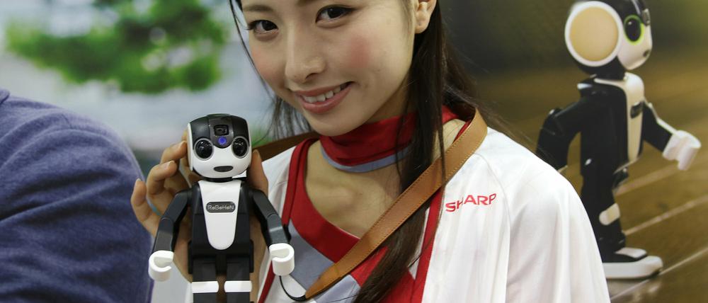 Eine Hostesse zeigt auf Japans führender Unterhaltungselektronik-Messe, Ceatec den kleinen Roboter RoBoHoN.