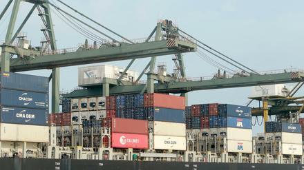 Container werden im Hafen auf ein Schiff verladen.