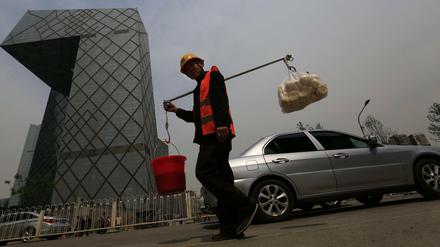 Ein chinesischer Bauarbeiter geht an einem der markantesten Bauwerken in Peking vorbei, dem Gebäude des chinesischen Staatsfernsehens CCTV.