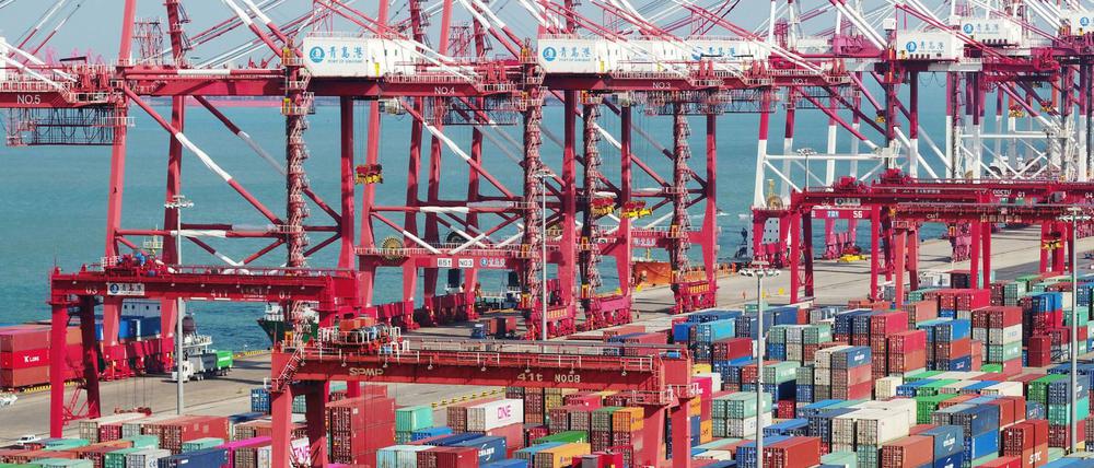China, Qingdao: In einem Hafen stehen Container und Containerbrücken.