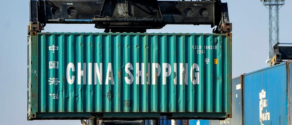 Ein Mann rangiert Container für die Weiterverladung in einer Logistikstation. 