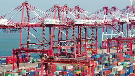 In einem Hafen im chinesischen Qingdao, China stehen Container und Containerbrücken. 