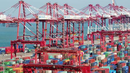 In einem Hafen im chinesischen Qingdao stehen Container und Containerbrücken.