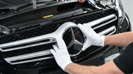 Ein Mitarbeiter von Mercedes-Benz bringt im Werk den Stern an einem Auto der C-Klasse an. 